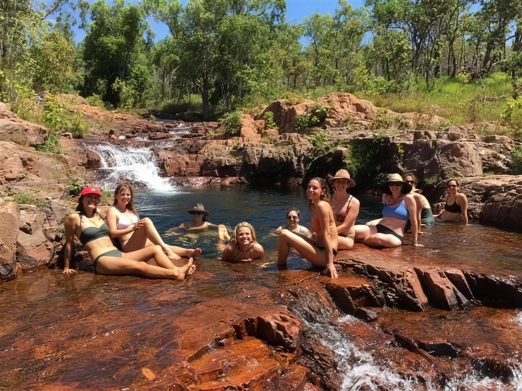 Women resting on warm rocks beside a waterhole